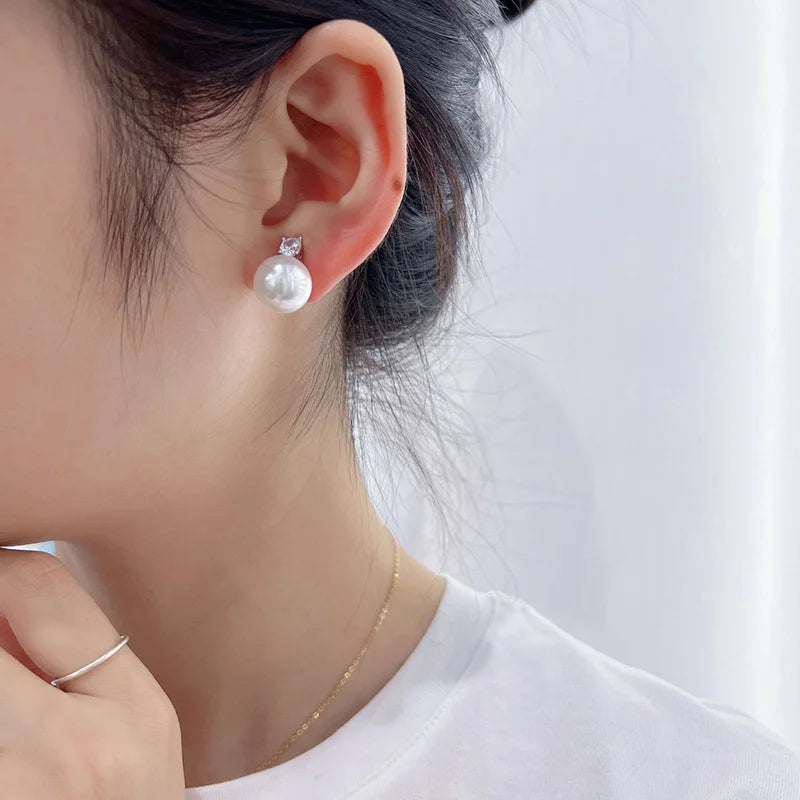 White pearl drop clip on earrings in silver side view on model wearing white shirt