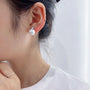 White pearl drop clip on earrings in silver side view on model wearing white shirt