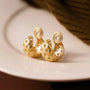 Gold woven crescent clip-on hoop earrings with spiral tops displayed on white ceramic dish