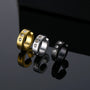 Zirconia bold clip on hoop earrings in silver, gold and black displayed at angle with reflective surface background