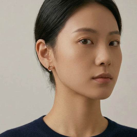 Close-up of a model wearing sculptural rose gold twisted earrings, showcasing the fluid design and light-catching solitaire stone.