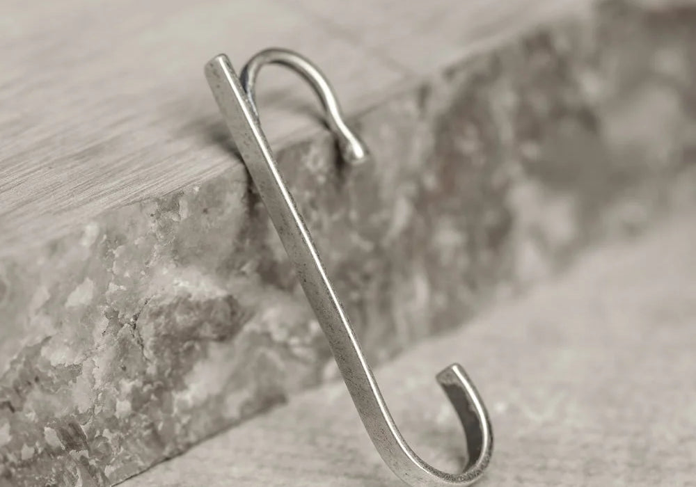 The Axis minimalist sterling silver ear cuff displayed leaning against a piece of grey stone, highlighting its shape.