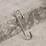 The Axis minimalist sterling silver ear cuff displayed leaning against a piece of grey stone, highlighting its shape.