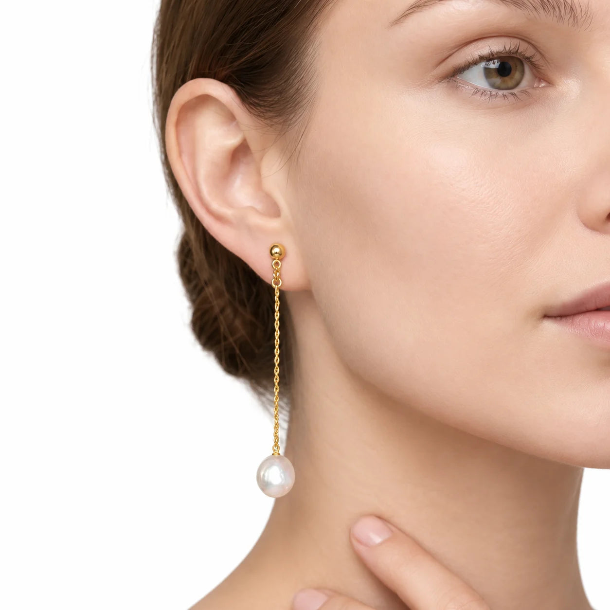 Gold baroque pearl chain drop clip-on earring worn on a non-pierced ear