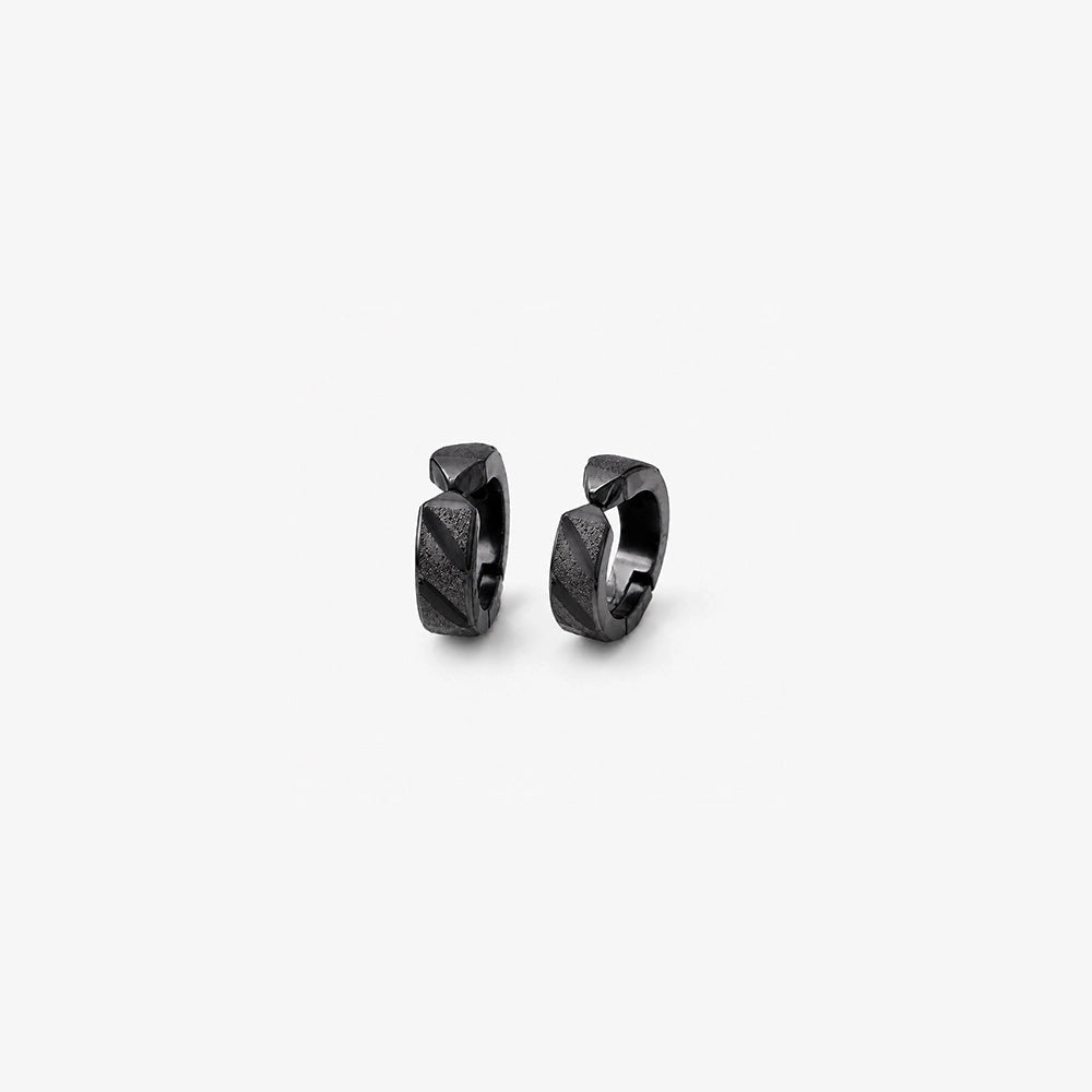 Close up detail of the diagonal faceted texture on black clip on huggie hoop earrings
