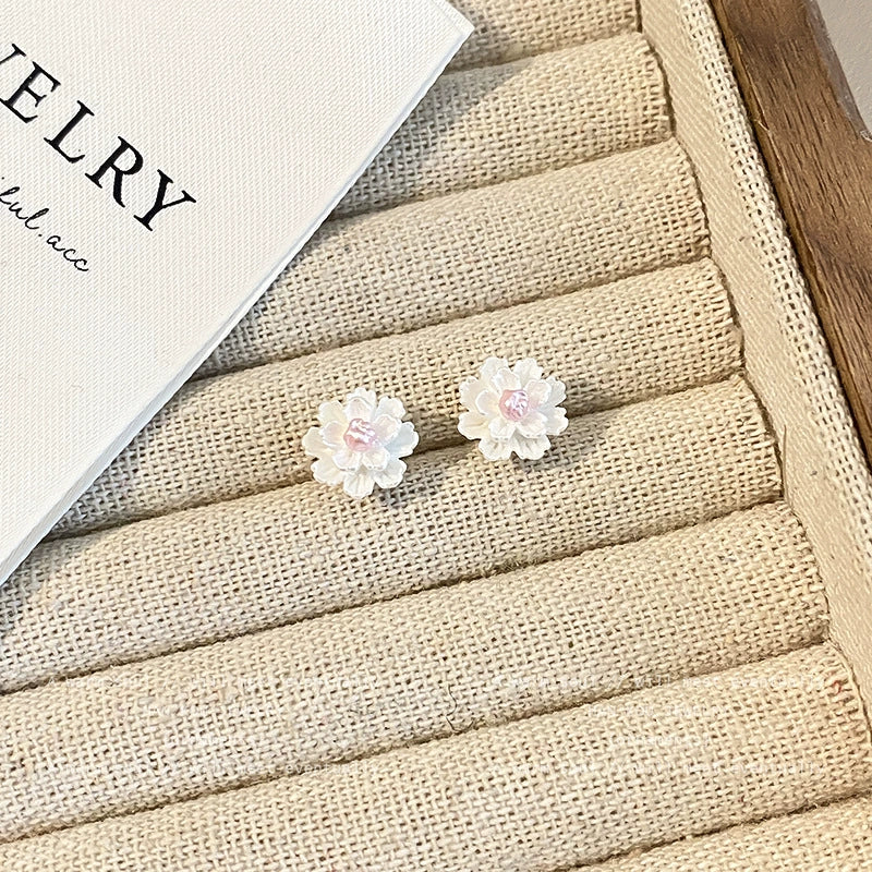Pair of white cluster petal magnetic stud earrings with pink centers displayed on a textured jewelry tray next to a "JEWELRY" card.