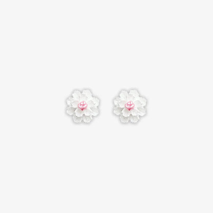 Isolated close-up of two white cluster petal magnetic stud earrings with vibrant pink centers on a clean white background.