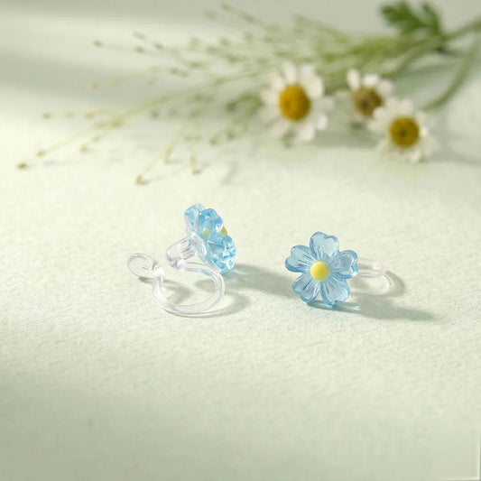 Pair of sky blue daisy candy color earrings with a translucent jelly finish on a soft textured background.