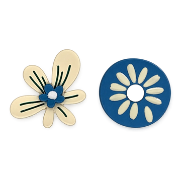 A pair of floral clip on earrings a white background. One is featuring a cream-colored five-petal flower with a blue center, white dot, and green leaf-like lines.