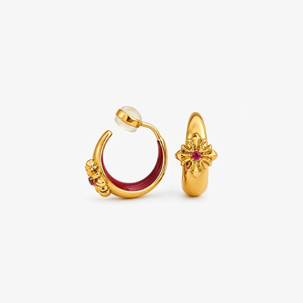 A pair of 16k gold-finished cross motif clip-on hoops with a deep crimson enamel lining and central stone.