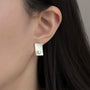 Brushed rectangle pearl clip-on stud worn on a non-pierced earlobe
