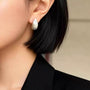 Brushed dome clip-on earring worn on a non-pierced earlobe with a black blazer