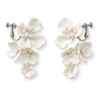 Flat lay front view of a matching pair of cascading handmade white ceramic flower clip-on bridal earrings with pearl clusters on polished silver-plated hardware, isolated on a clean white background.