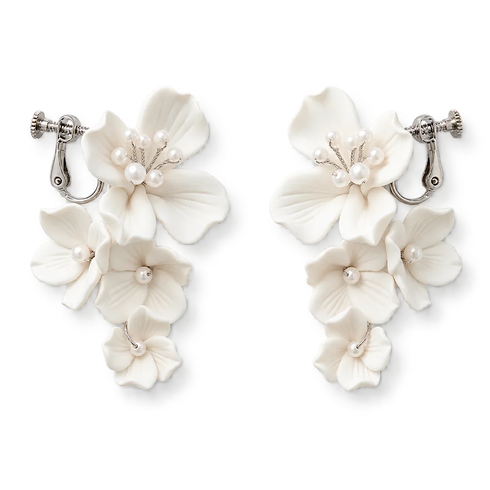 Flat lay front view of a matching pair of cascading handmade white ceramic flower clip-on bridal earrings with pearl clusters on polished silver-plated hardware, isolated on a clean white background.
