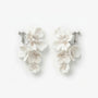 Flat lay front view of a matching pair of cascading handmade white ceramic flower clip-on bridal earrings with pearl clusters on polished silver-plated hardware, isolated on a clean white background.