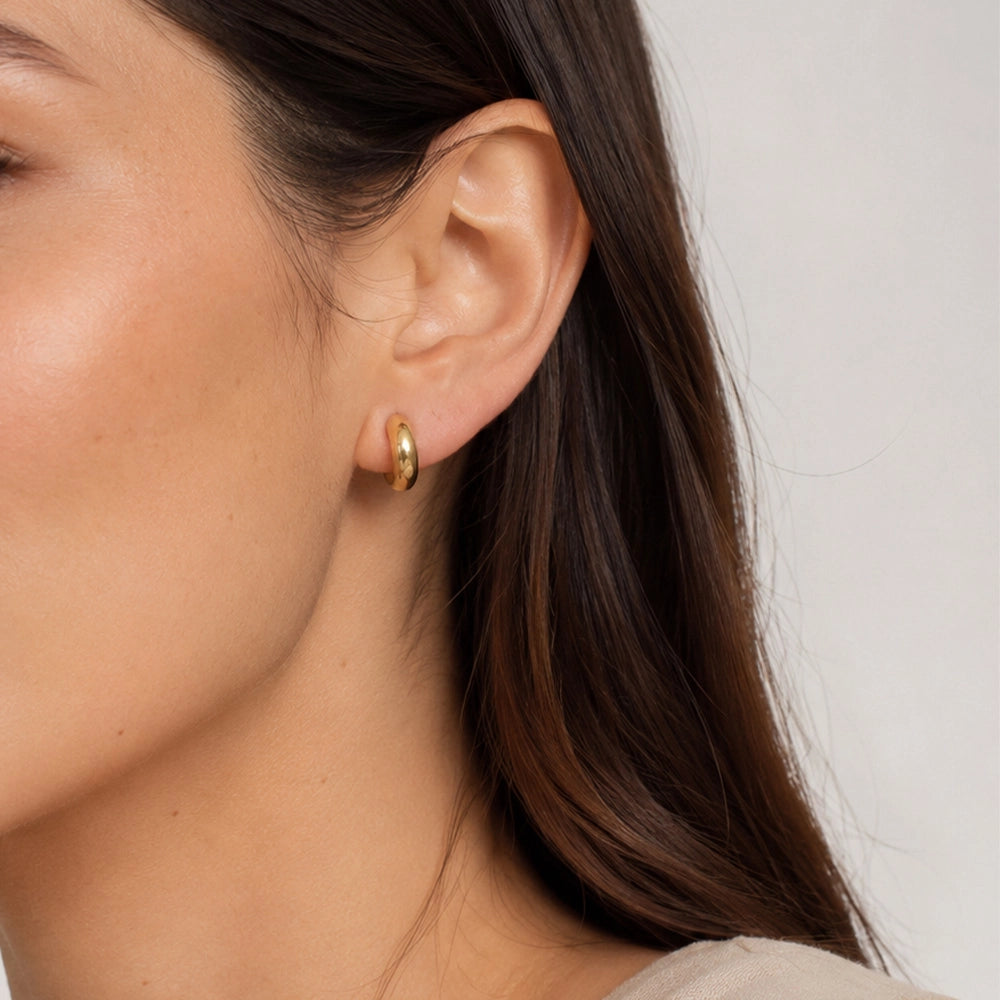 Woman wearing a chunky gold clip on huggie hoop earring on a non pierced ear