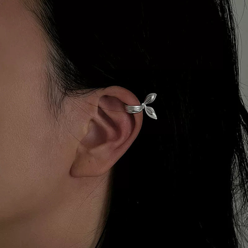A model wearing the radiant silver ribbon ear cuff low on the lobe, showing the cool-toned liquid metal effect of the non-pierced statement.