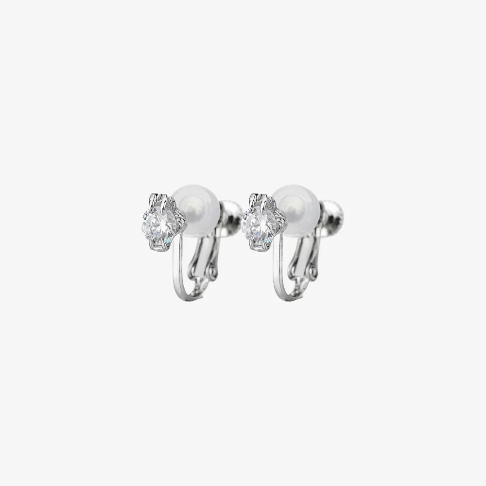A pair of classic solitaire clip-on stud earrings with clear, round-cut cubic zirconia stones and comfortable cushioned backs, shown on a white background.