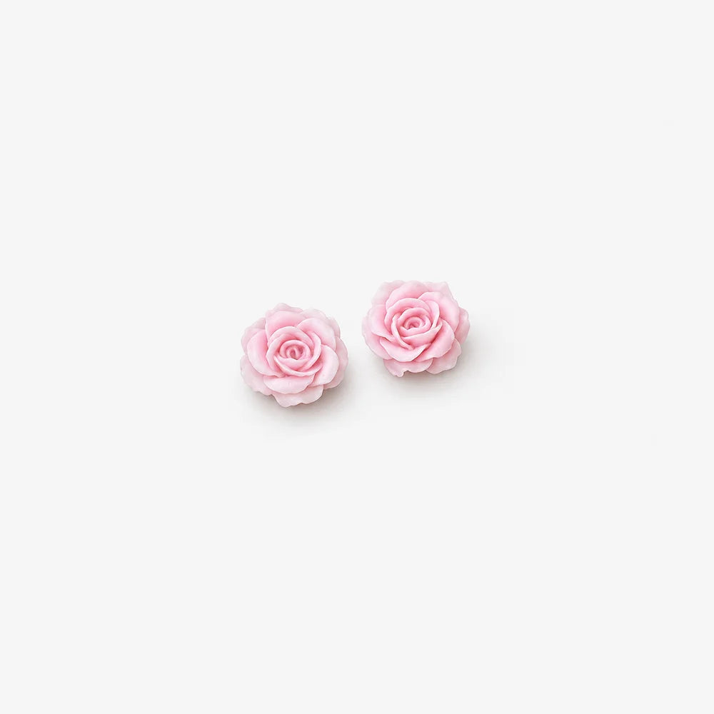 A pair of light pink rose stud earrings on a clean, solid off-white background.