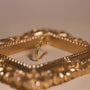 A lifestyle photo showing the delicate gold bow ear cuff resting inside a decorative gold picture frame.