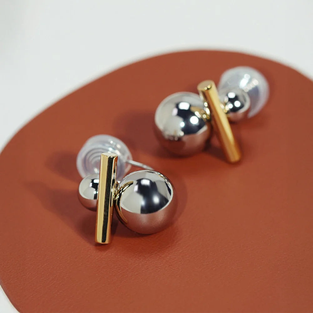 Dual-Tone Sphere and Bar Clip-On Earrings displayed on terracotta surface, angled view