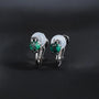 Une paire de boucles d'oreilles élégantes à clips en zircon cubique vert émeraude, serties dans une monture argentée et dotées de fermoirs à clips rembourrés confortables.