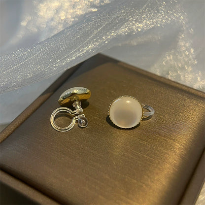 A close-up of the Lumi Frosted Moonstone invisible clip-on earrings, highlighting the luminous stone and the clear, comfortable clip mechanism.