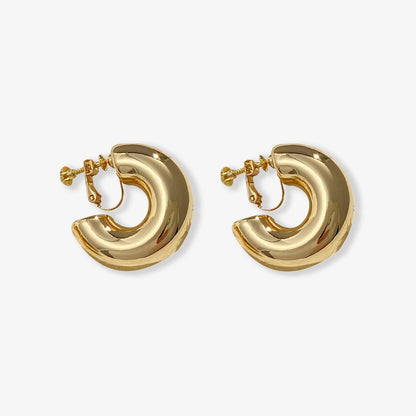 Gold-toned bold hoop clip-on earrings, modern style with a screw-back closure made from copper alloy. Ideal statement huggie earrings for those seeking a classic yet striking accessory.