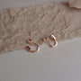 Rose gold earrings with comfortable clip on design on a textured beige surface