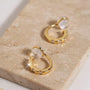 Close-up of yellow gold finished CZ clip-on huggies on a stone surface, highlighting the sparkle and comfort c-type clip on.