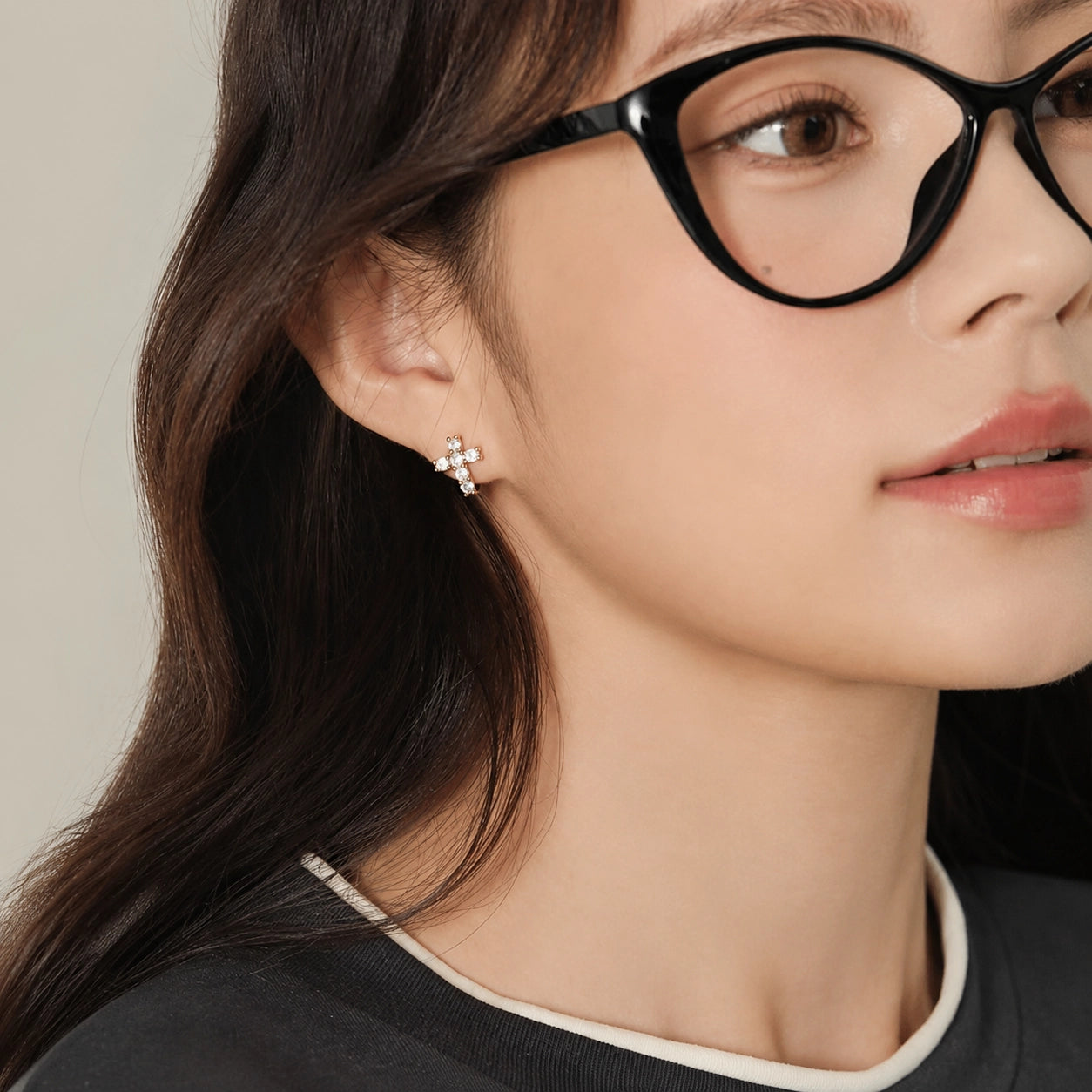 Woman in glasses wearing a gold CZ cross clip on earring on a non pierced ear