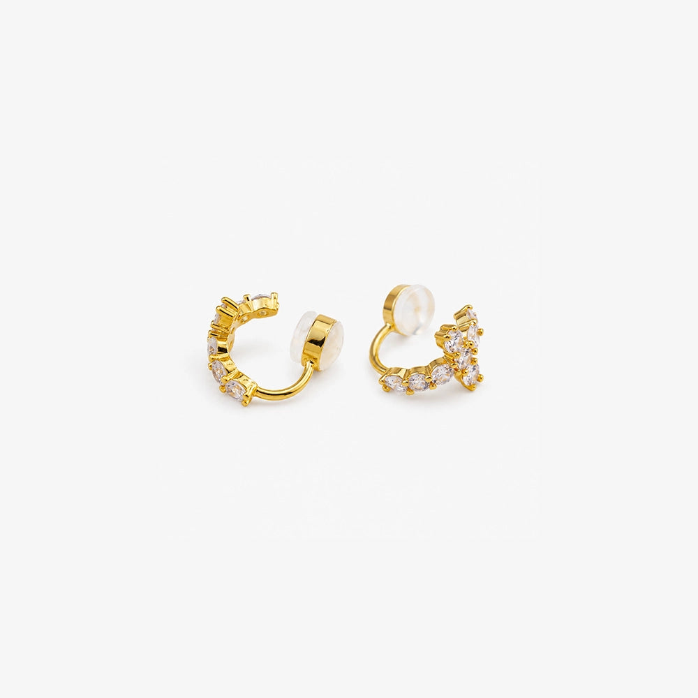Detail of pavé cubic zirconia cross on gold clip on huggie hoop earrings