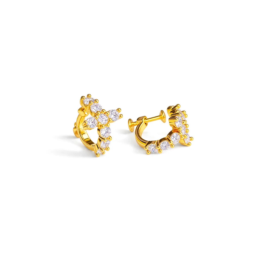 A pair of gold huggie hoop earrings adorned with clear cubic zirconia stones, displayed on a clean white background.