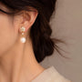 Woman wearing a gold flower and pearl drop clip on earring on a non pierced ear