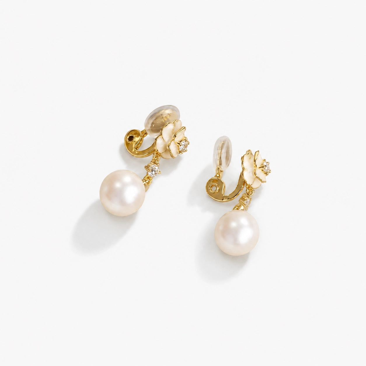 Detail of the enamel flower and shell pearl on gold clip on drop earrings