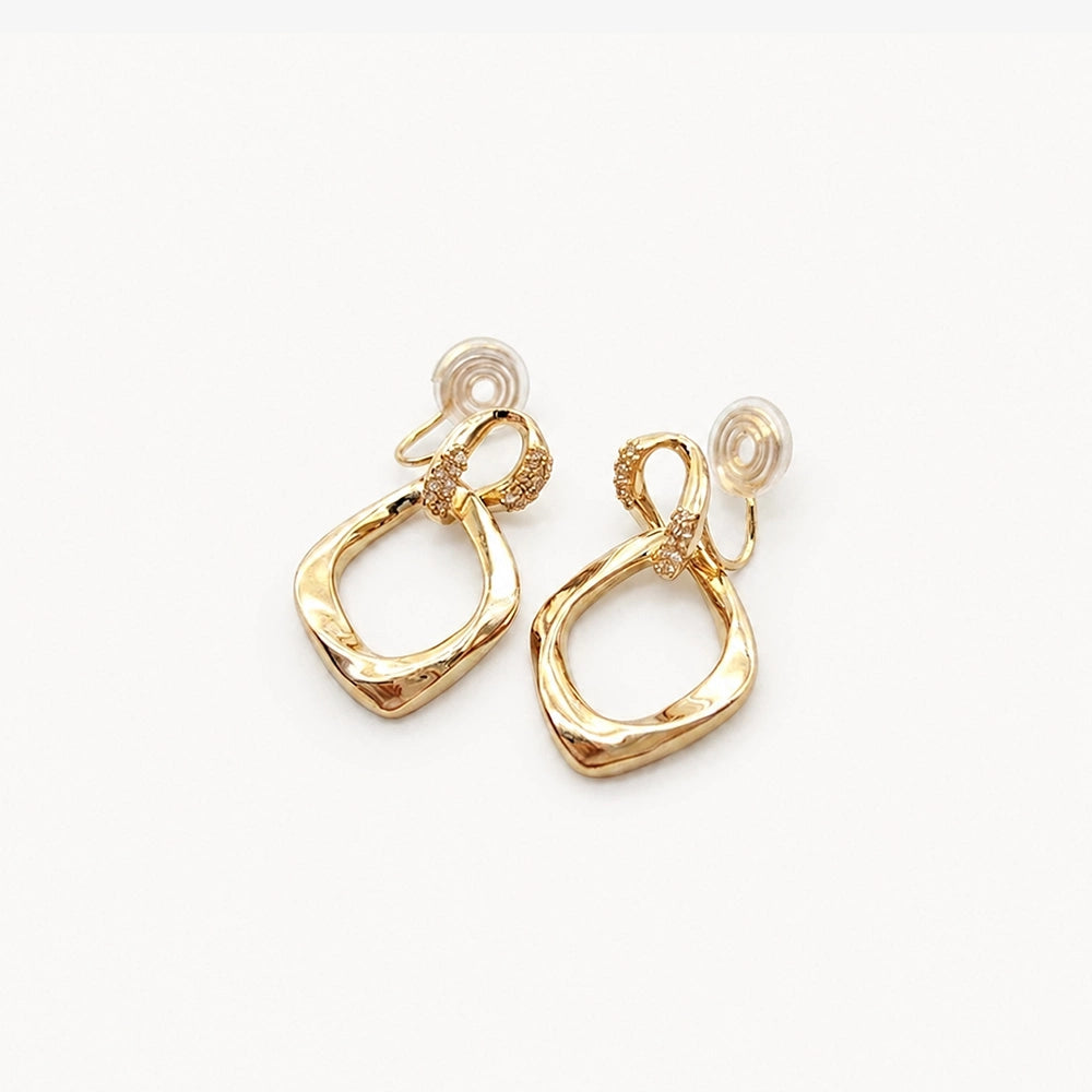 The back view of the gold geometric drop earrings, clearly showing the comfortable and adjustable clip-on mechanism with its silicone pad.