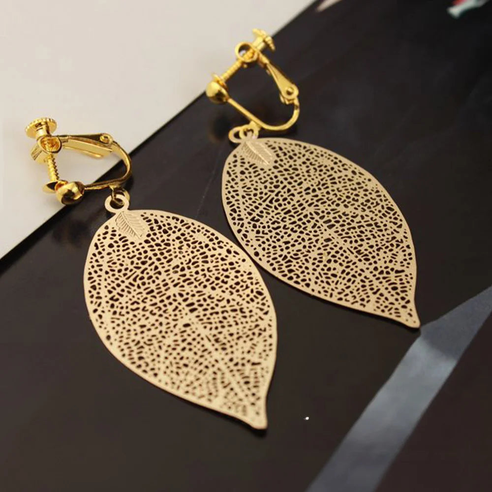Gold Leaf Clip On Earrings displayed on black background showing filigree leaf design with detailed cutout pattern and gold-tone finish