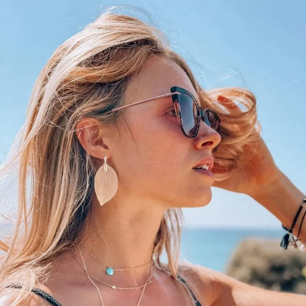 Gold Leaf Clip On Earrings worn by woman at beach, side profile view with sunglasses