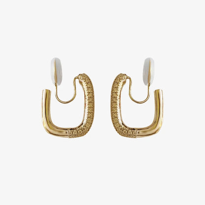 A pair of gold pavé square clip-on hoop earrings with white comfort pads, shown on a white background.