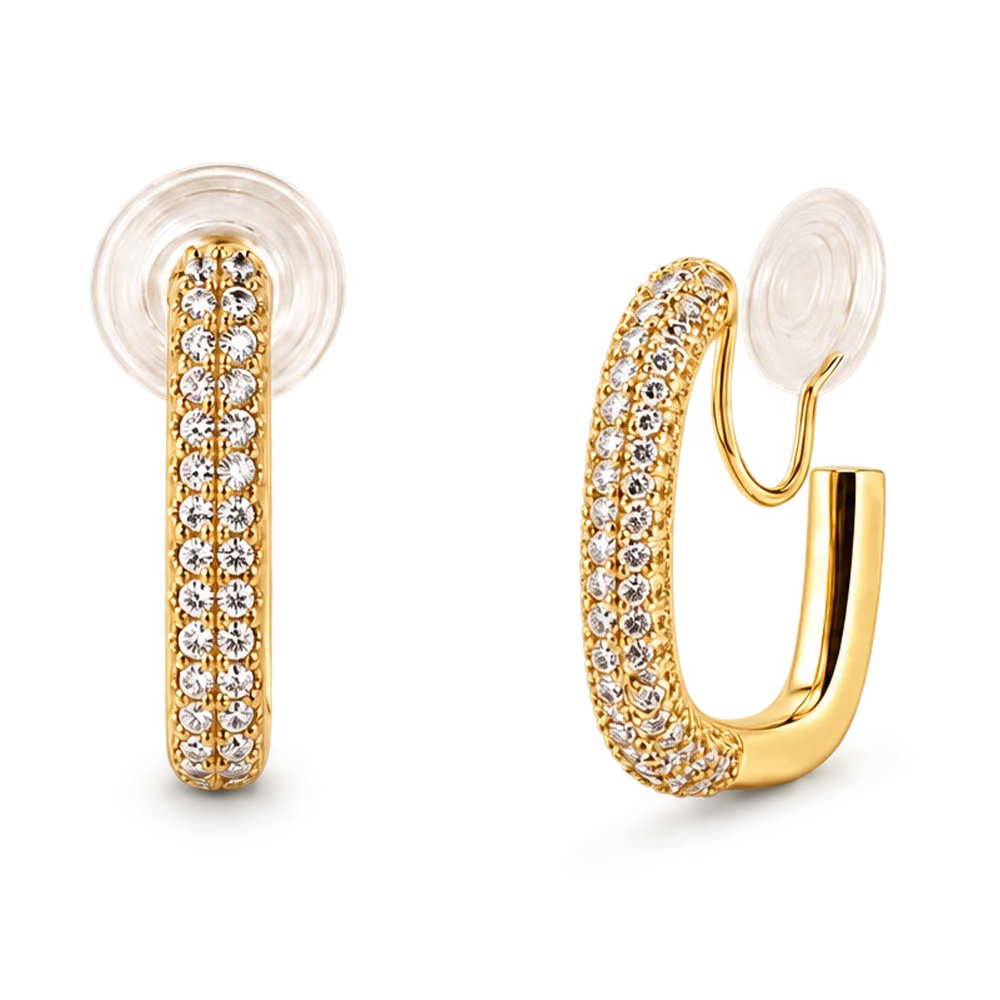 A pair of gold huggie hoop earrings adorned with pavé-set clear cubic zirconia stones, featuring a clear textured silicone ear plug, shown on a solid white background.