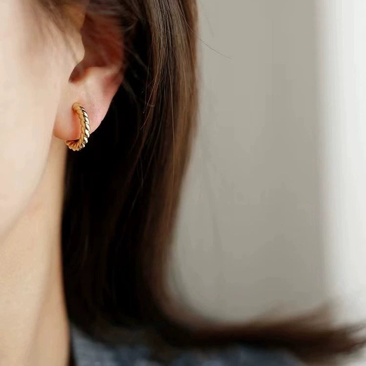 Woman wearing a gold twisted rope clip on hoop earring on a non pierced ear