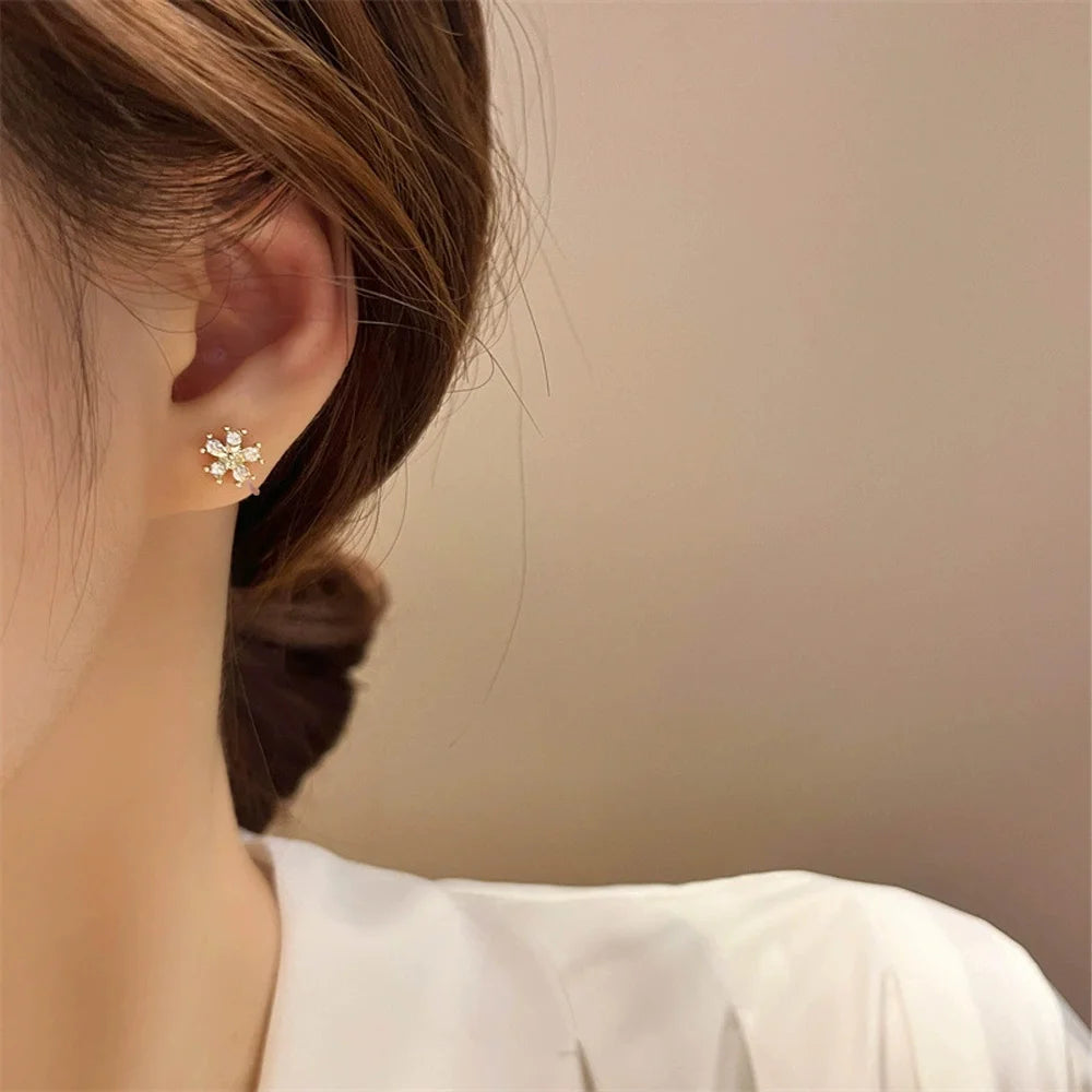 A close-up of a model's ear wearing a Golden Snowflake Crystal invisible clip-on earring, showcasing its delicate sparkle and comfortable fit.