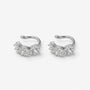 A pair of silver-toned huggie hoop earrings with a cluster of clear pavé-set round gemstones, shown on a light gray background.