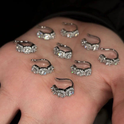 A collection of Halo Nova silver triple zircon pavé clip-on ear cuffs displayed on an open hand, showcasing their brilliant sparkle and design.