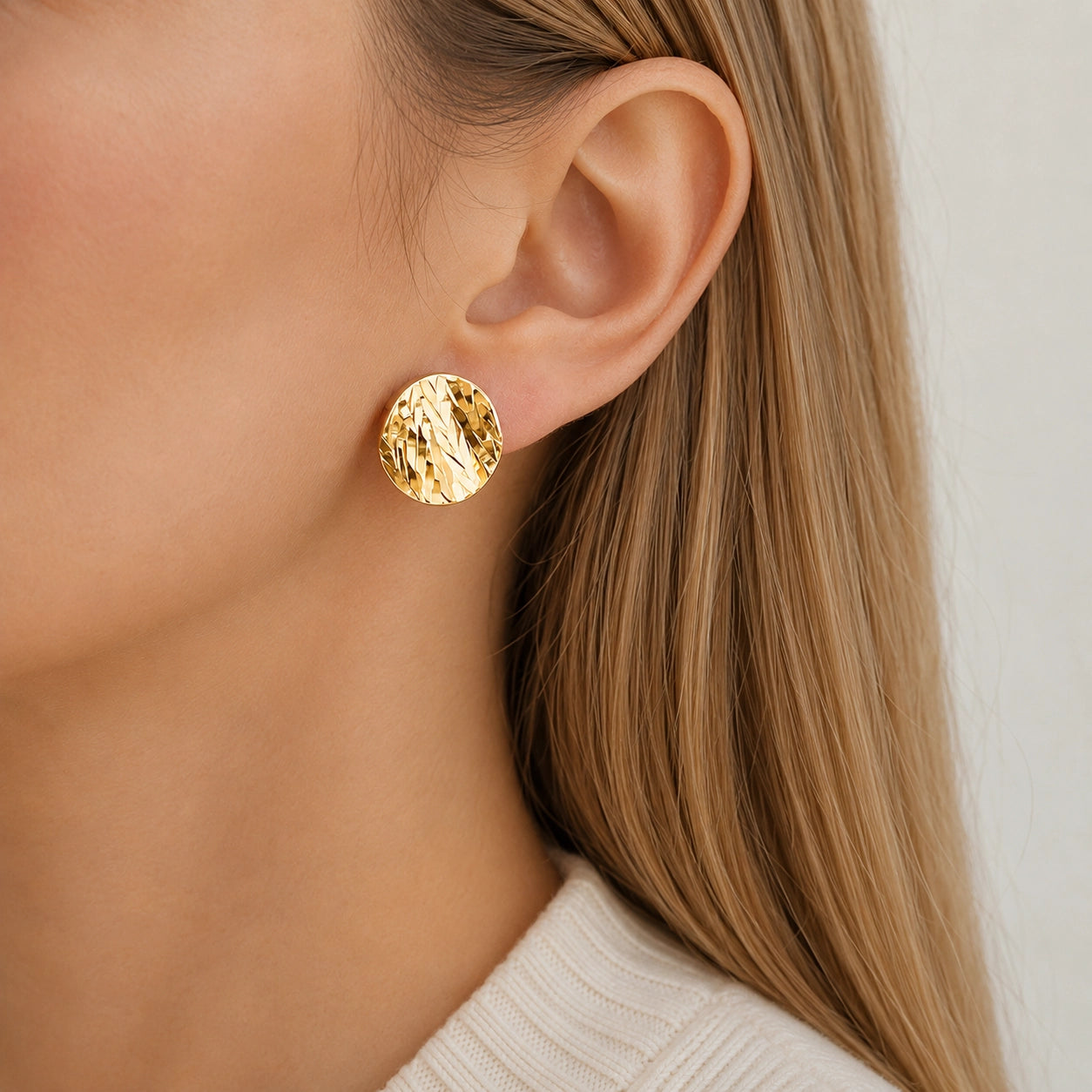 Woman wearing a hammered gold disc clip on earring on a non pierced ear