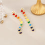 Rainbow Heart Cascade Clip On Earrings displayed at angle showing colorful enamel hearts in rainbow gradient order on gold background