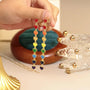 Rainbow Heart Cascade clip-on earrings held in hand, featuring colorful enamel hearts in red, orange, yellow, green, blue and purple on gold-tone chain links