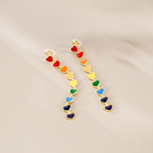 Gold cascade earrings with heart-shaped charms in rainbow hues, celebrating LGBTQ pride. These lgbtq earrings are a beautiful statement piece or gift for anyone supporting LGBTQ inclusivity and pride.