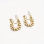 Pair of gold honeycomb clip-on hoop earrings angled to show the clear hexagonal patterns on a white surface.