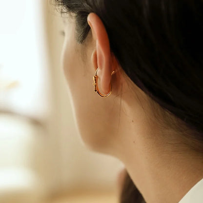 A view from behind of a model showing how the gold bow ear cuff wraps around the cartilage.